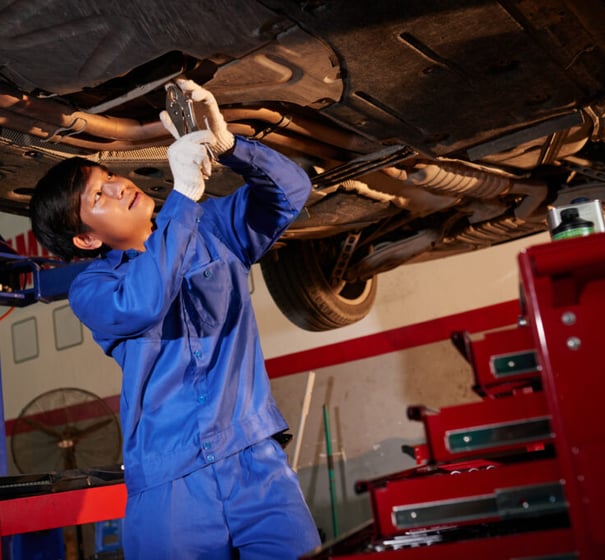 man inspecting under a car