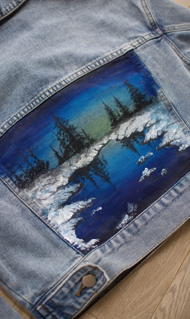 a denim jacket with a painting of a blue sky