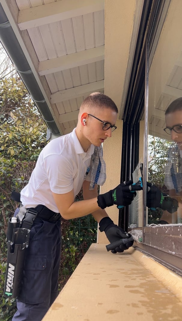 Une personne qui nettoie les vitres d'un particulier. 