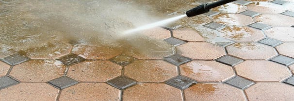 a person using a hose to clean a brick floor