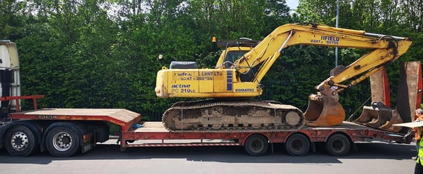 yellow digger loaded on the back of a van in dudley