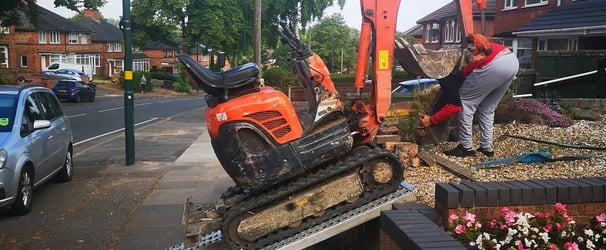 mini digger being loaded into a garden in dudley