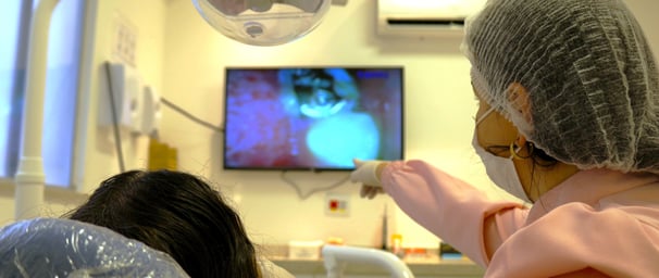 a woman in a hospital room with showing the patients teeth on the screen