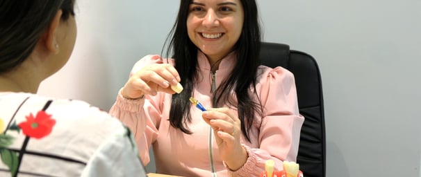 a woman in a pink shirt is sitting at a table with a dental implant on her hands