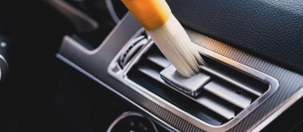 a person cleaning a car's dashboard with a brush