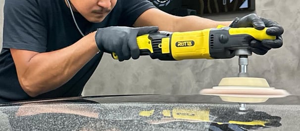 a man in a black shirt and gloves is using a sandblaker