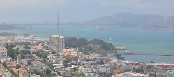 a view of  the golden gate bridge spanning the width of a city