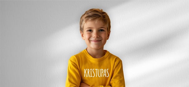 vaikas su geltonu dzemperiu ant kurio yra parasytas vardas Kristupas