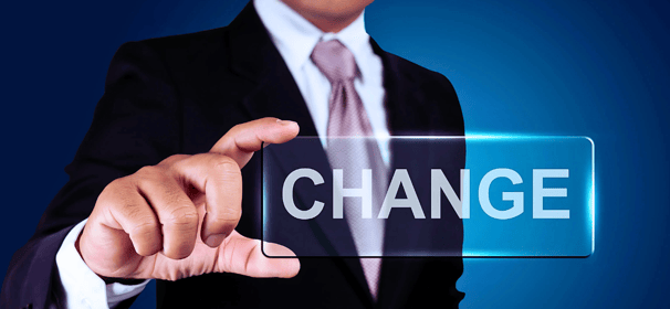 A businessman in a suit and tie holds up a rectangular piece of glass with the word "Change" written on it, face unseen.