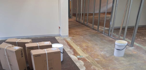 Office interior in early renovation phase with floor preparation and drywall framing.