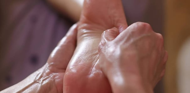 Massage du pied, geste lent et précis pour relâcher les tensions et inviter au lâcher-prise.