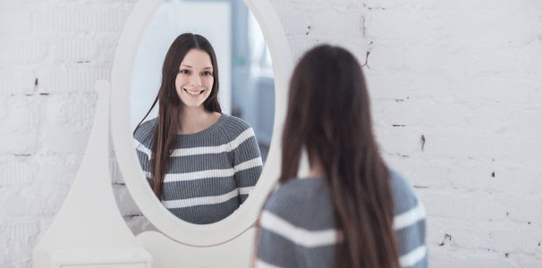 Mujer joven contemplándose al espejo. Se nota contenta consigo misma, buena autoestima.