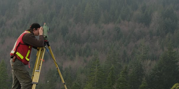 a man in a red vest and a yellow vest is holding a tripod