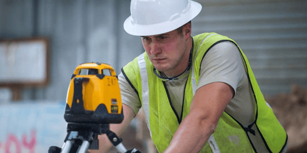 a man in a hard hat and safety vest holding a laser level