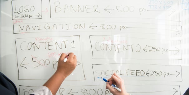 Two team members are planning the layout of a website on a whiteboard 