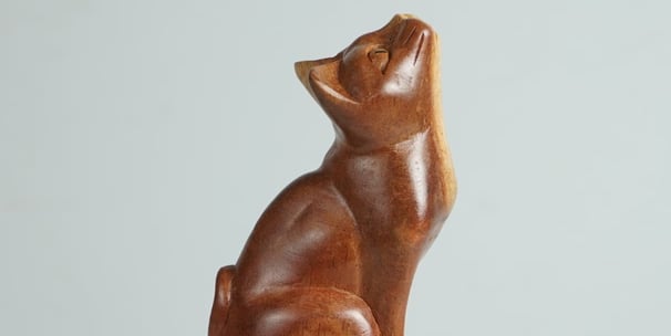 a wooden cat statue of a cat sitting sculpture on a pedestal
