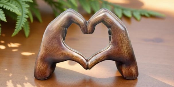 a wooden heart shaped ornament with two hands holding hands