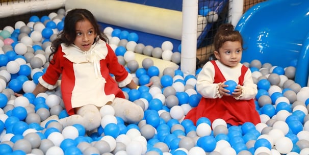 two young girls in red and white dresses playing in a ball pit in gurugram trumpy softplay