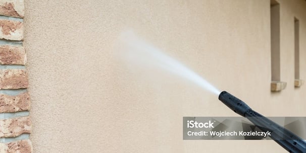 a person using a pressure gun to clean a house