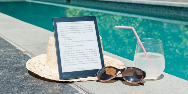 a tablet with a straw hat and sunglasses next to a book