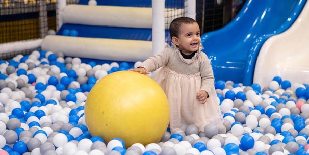 a baby girl in a ball pit with a ball in the middle of a ball