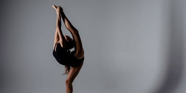 A young gymnast performing a balance with the leg lifted.