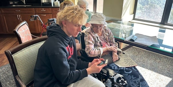 teen helps older woman learn dictation on her iphone