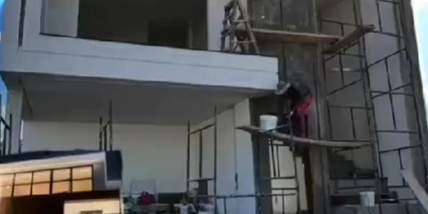 a man is standing on a scaffold of bricks