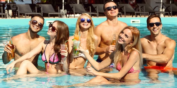 Group of friends enjoying drinks in a pool, representing the fun and social vibe of both private and public Vegas crawls.