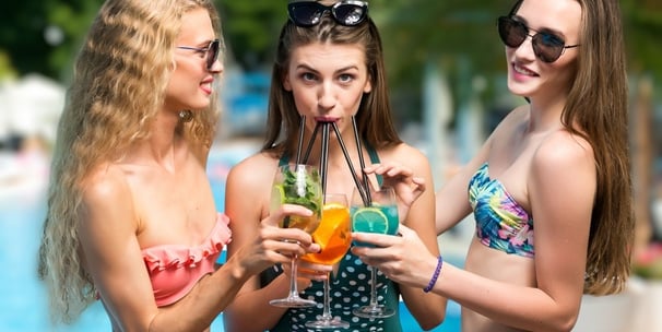 Women sharing colorful drinks poolside, perfect for Vegas dayclub survival tips