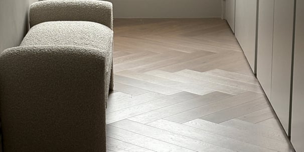 A light oak herringbone floor with a small chair