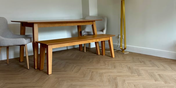 A medium oak colour herringbone LVT floor with a table and chairs