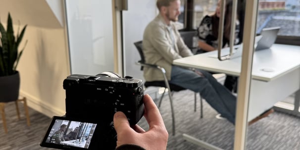 a person holding a camera and taking a picture of a man in a chair