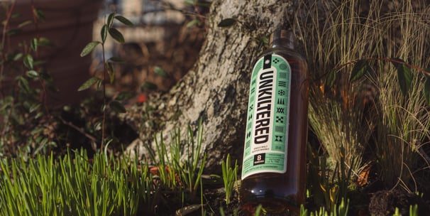 a bottle of whisky sitting on the ground next to a tree