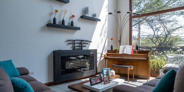 fotografía inmobiliaria quito ecuador tumbaco gran sala de estar con muebles, piano y un gran ventanal con luz natural