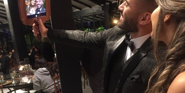 Um homem e uma mulher tirando uma selfie com espelho de mão em uma festa.