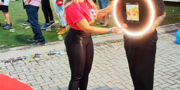 Uma mulher segurando totem de fotos móvel em um evento de marketing.