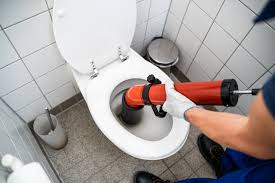 a man in a blue shirt is using a plunger