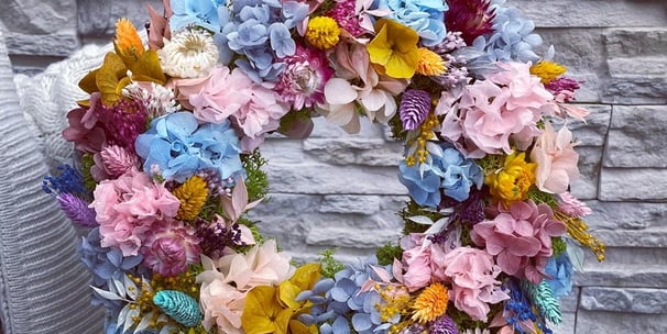 a wreath of flowers on a chair in front of a brick wall