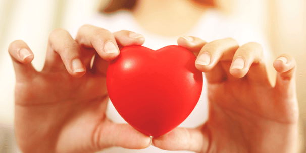 Dos manos en primer plano sosteniendo con cuidado un corazón de juguete. Da a entender que se cuida