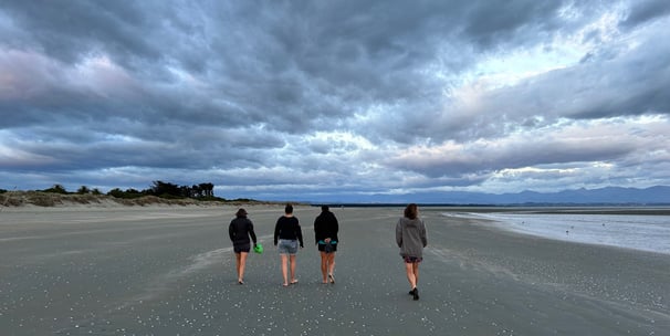 four women walking on a beach