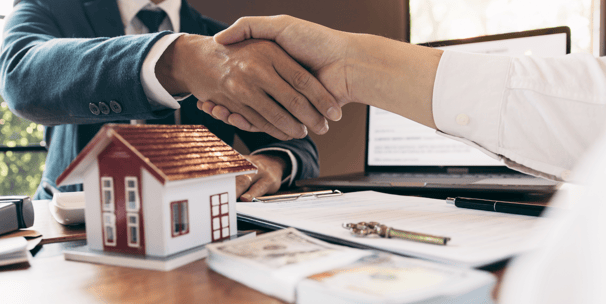 Poignée de main entre deux partenaires scellant la vente d’un hôtel touristique aux Caraïbes, symbolisant une transaction réu