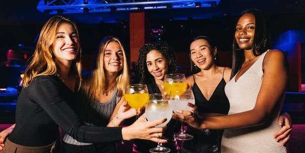 Group of women toasting with cocktails during a hosted nightlife crawl in Downtown Las Vegas.