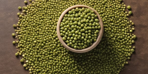 A close-up of peanuts coated in chili powder is placed on a wooden surface. Surrounding these are mounds of coarse salt and chili powder. Lime wedges are arranged in the background, adding a fresh contrast to the scene.