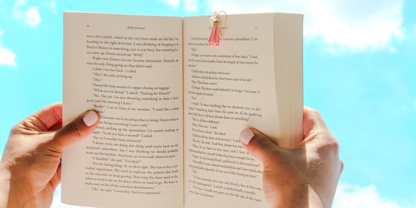a person holding a book with a clip bookmark on it