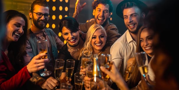 Smiling group of friends clinking champagne glasses at a lively downtown crawl Las Vegas bar during a DTLV Crawl.