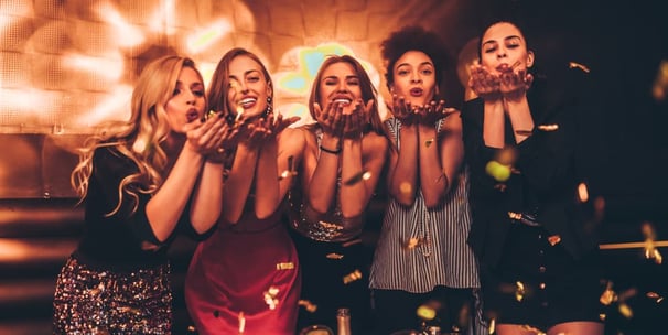 Group of stylish women blowing kisses surrounded by confetti during a glamorous night out on the Las Vegas Strip Crawl.