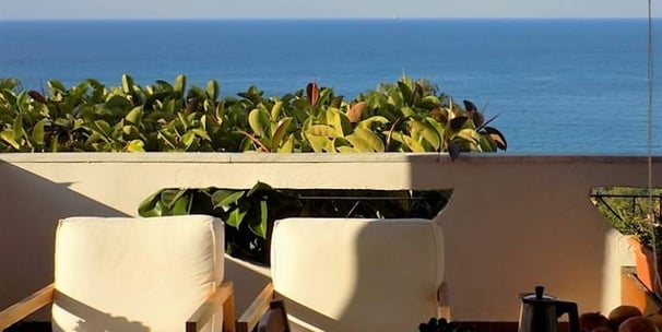 a balcony with a table and chairs and a view of the ocean