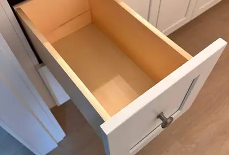 Open  box  inside a white shaker cabinet, showing solid wood construction and smooth finish.