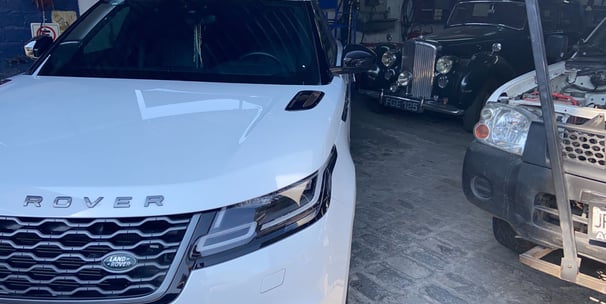 a white car parked in a garage with a man standing next to it